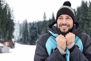 Photo of Happy man in warm clothes outdoors, space for text. Winter vacation