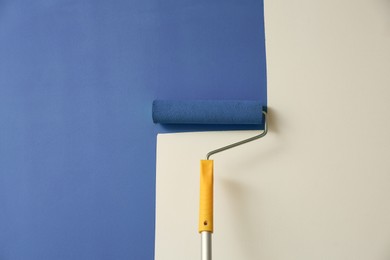 Applying green paint with roller brush on white wall