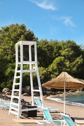 Lifeguard tower among loungers on sea beach