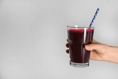 Photo of Woman with glass of delicious beet juice on grey background, closeup. Space for text