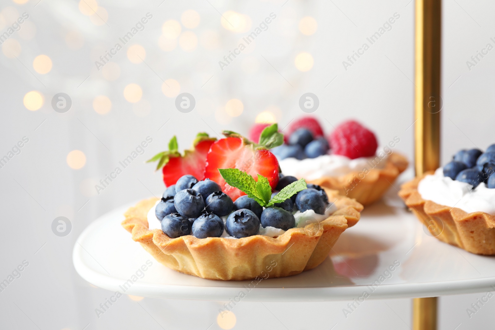 Photo of Tarts with different berries on cake stand. Delicious pastries