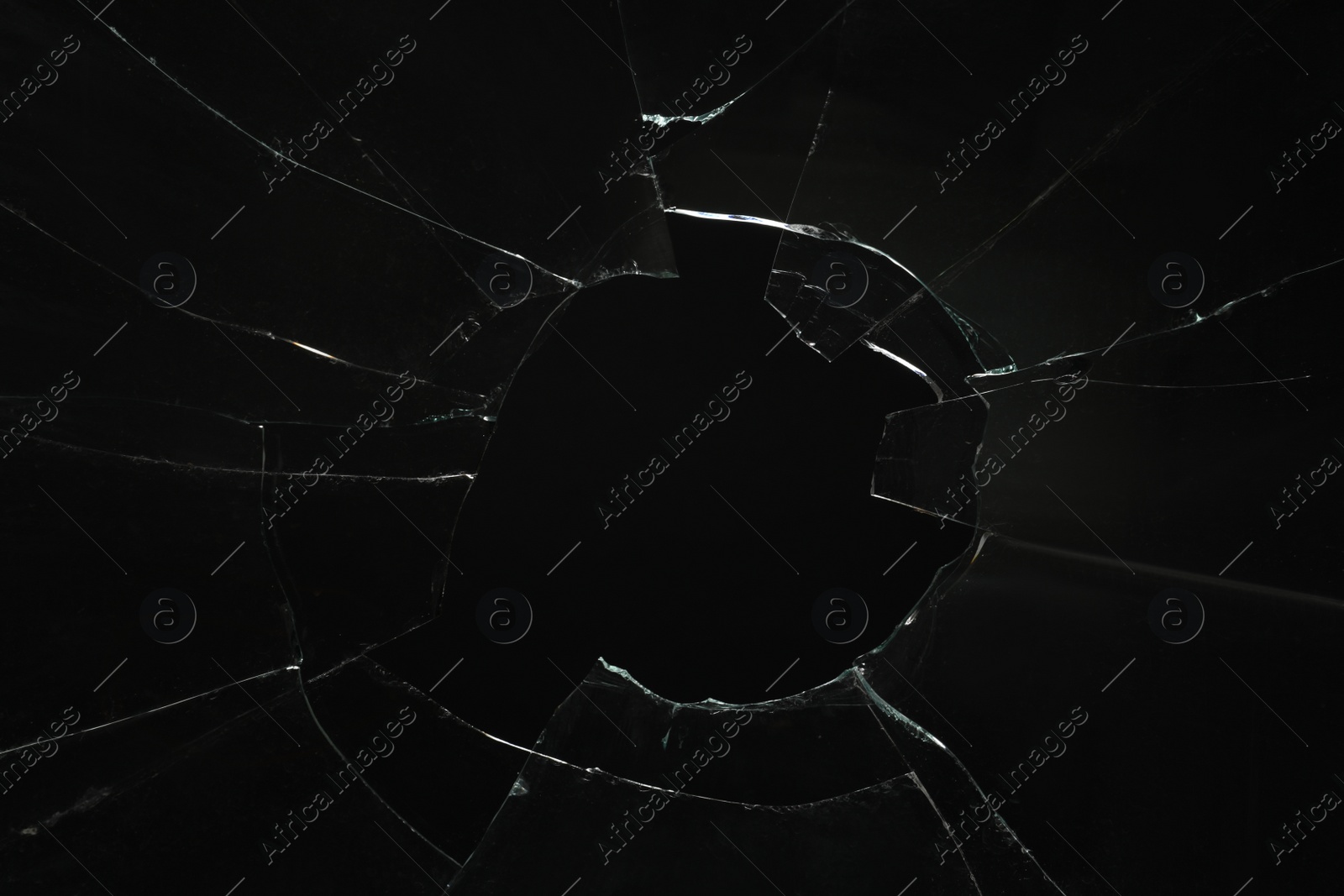Photo of Closeup view of broken glass with cracks on black background