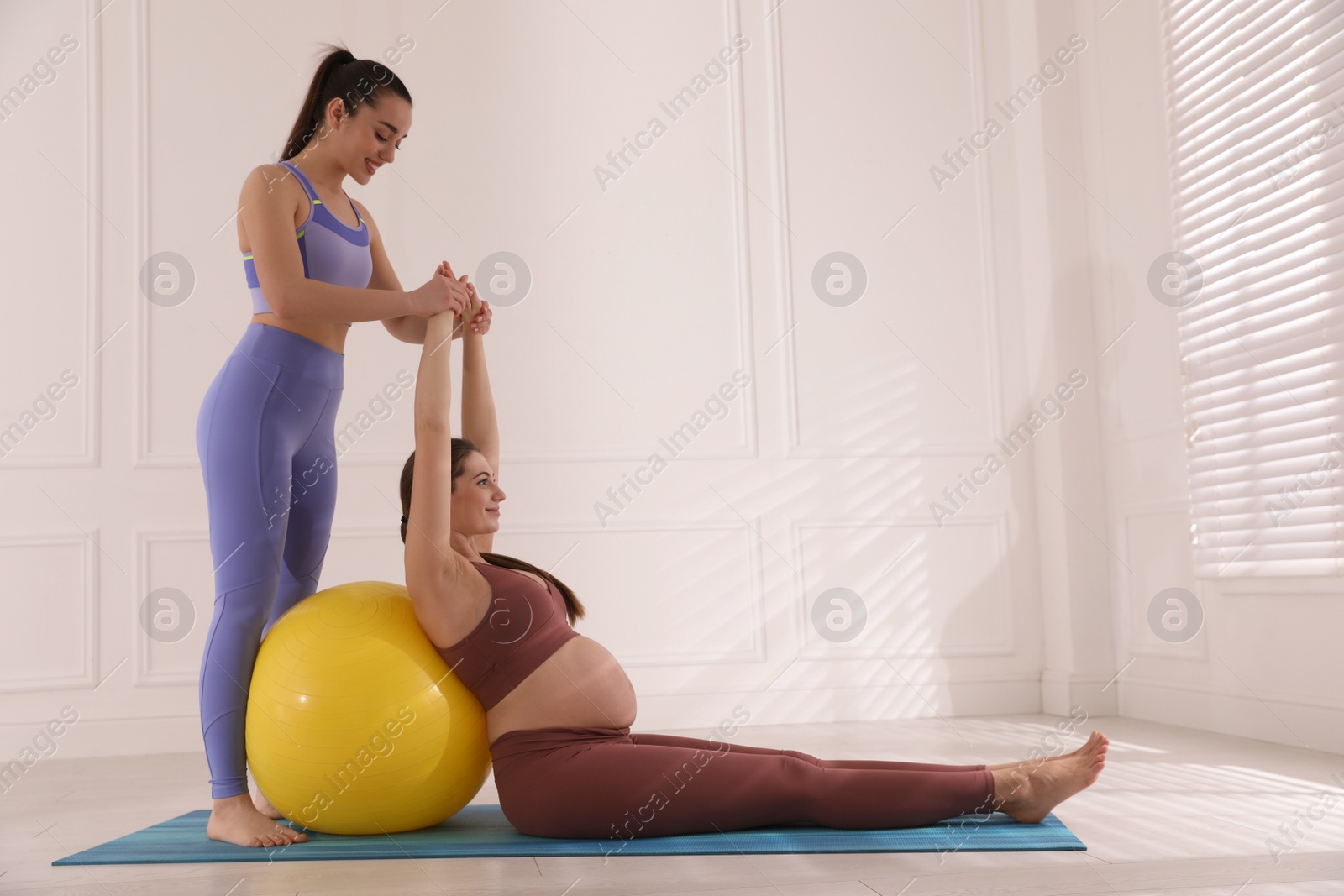 Photo of Trainer working with pregnant woman in gym. Preparation for child birth