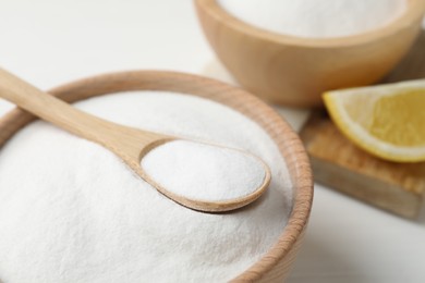 Photo of Baking soda and lemon on white wooden table, closeup