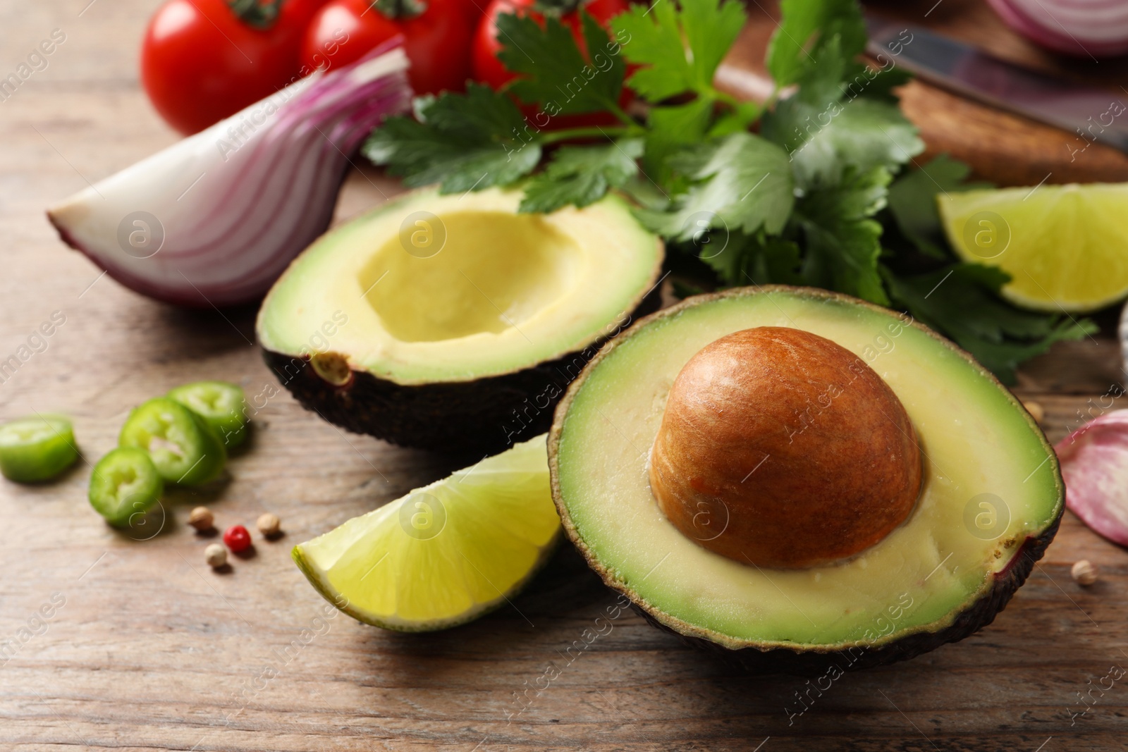 Photo of Fresh ingredients for guacamole on wooden table, closeup