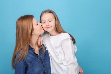 Photo of Portrait of mother and her cute daughter on light blue background. Space for text