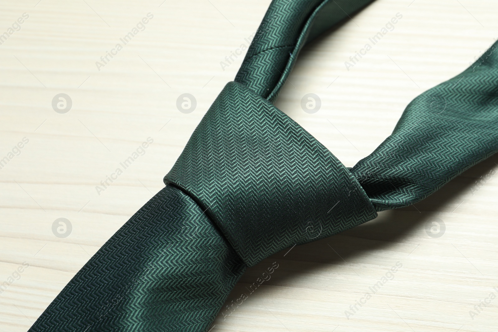 Photo of One green necktie on white wooden table, top view