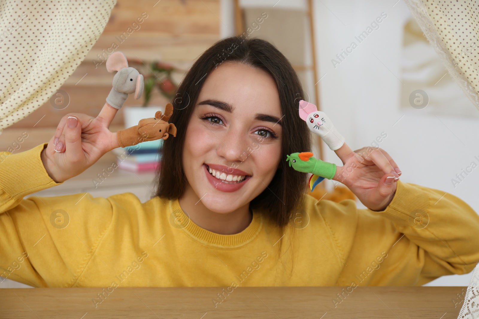 Photo of Young woman performing puppet show at home