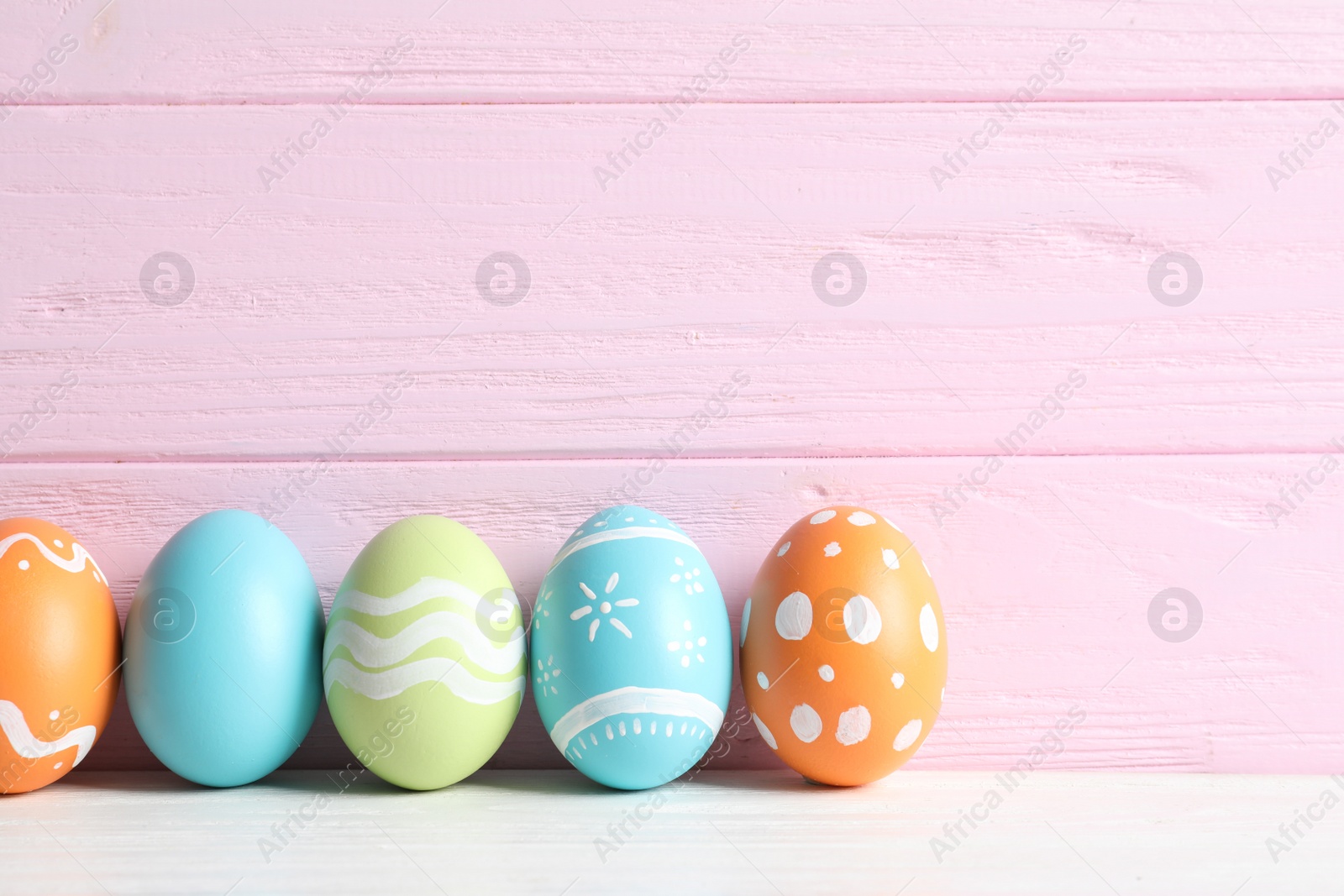 Photo of Colorful painted Easter eggs on table against wooden background, space for text