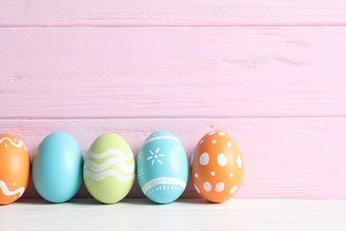 Colorful painted Easter eggs on table against wooden background, space for text