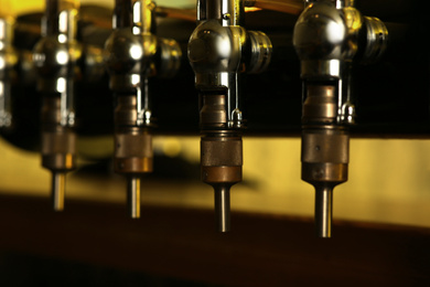 Photo of New modern beer taps in pub, closeup. Professional bar equipment