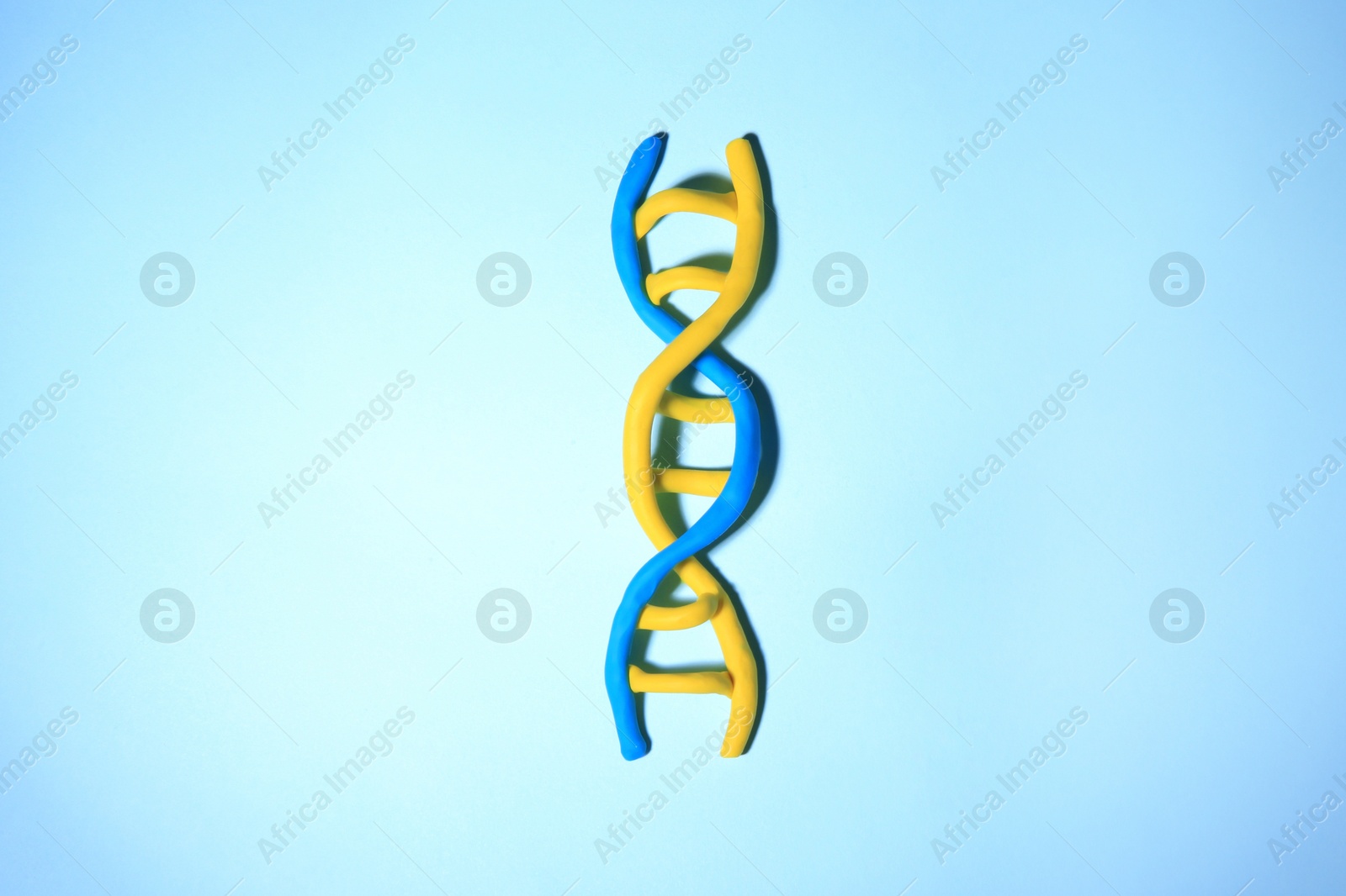 Photo of DNA molecule model made of colorful plasticine on light blue background, top view