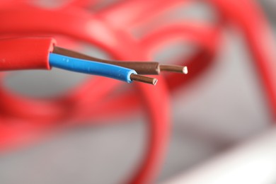 Photo of Colorful electrical wire on blurred background, closeup. Space for text