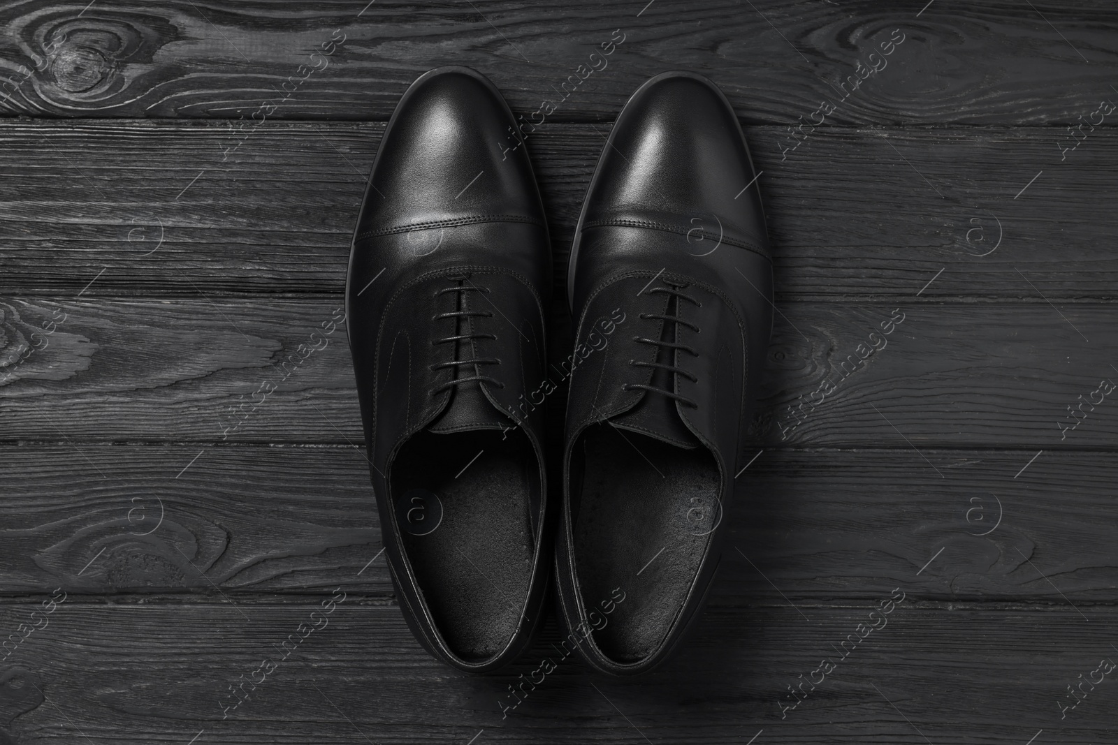 Photo of Pair of leather men shoes on black wooden background, top view