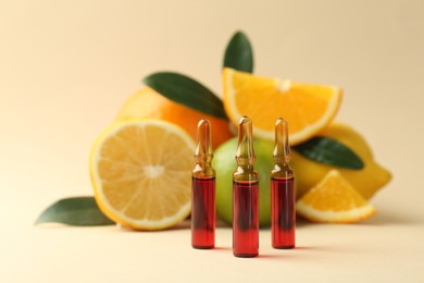 Skincare ampoules with vitamin C, different citrus fruits and leaves on beige background