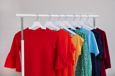 Photo of Wardrobe rack with different bright clothes on light background