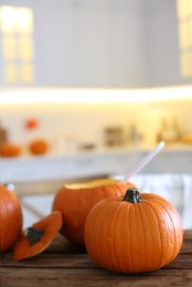 Photo of Fresh ripe pumpkins on wooden table in kitchen, space for text. Halloween celebration