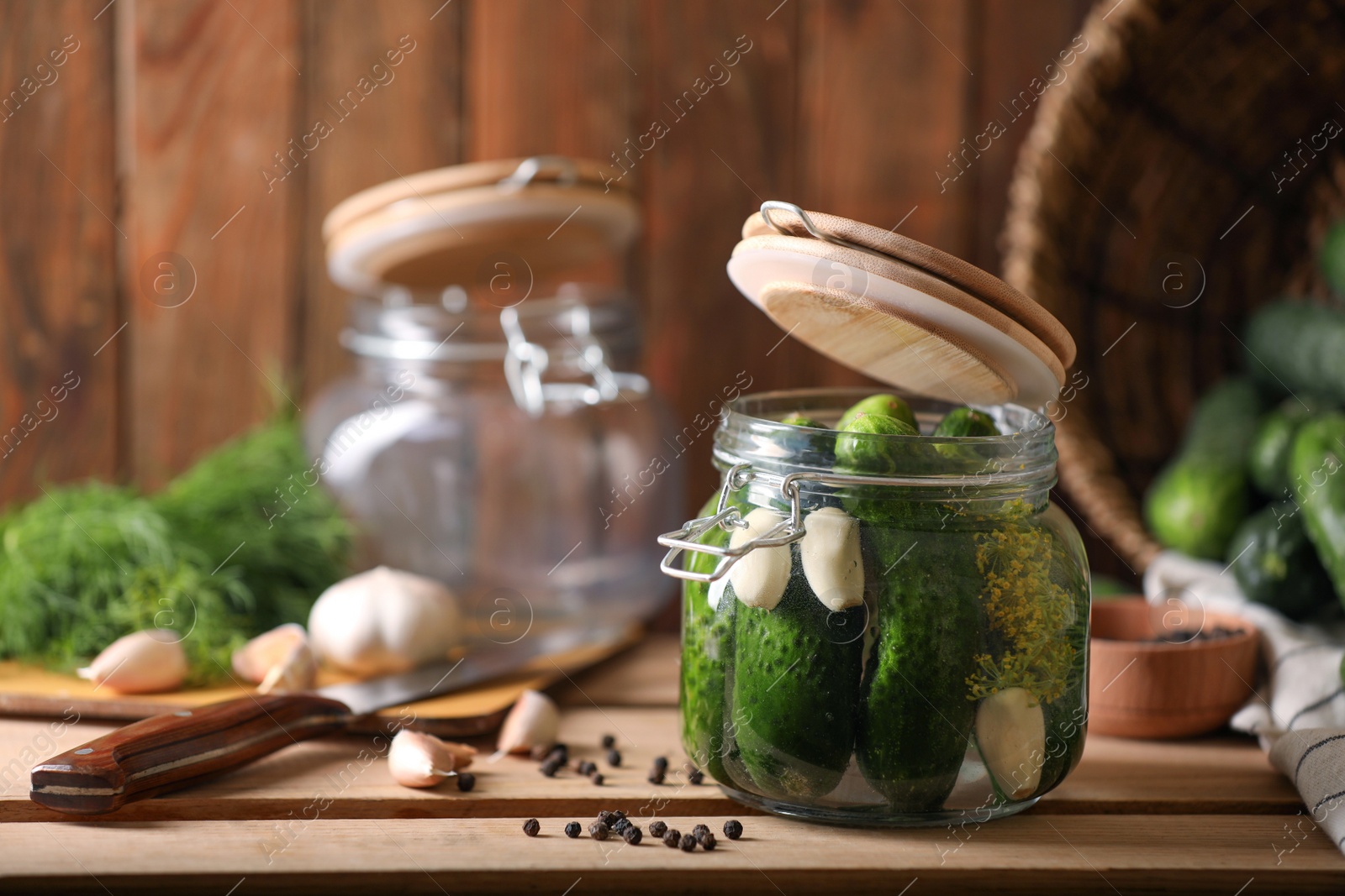 Photo of Glass jar with fresh cucumbers and other ingredients on wooden table. Canning vegetable