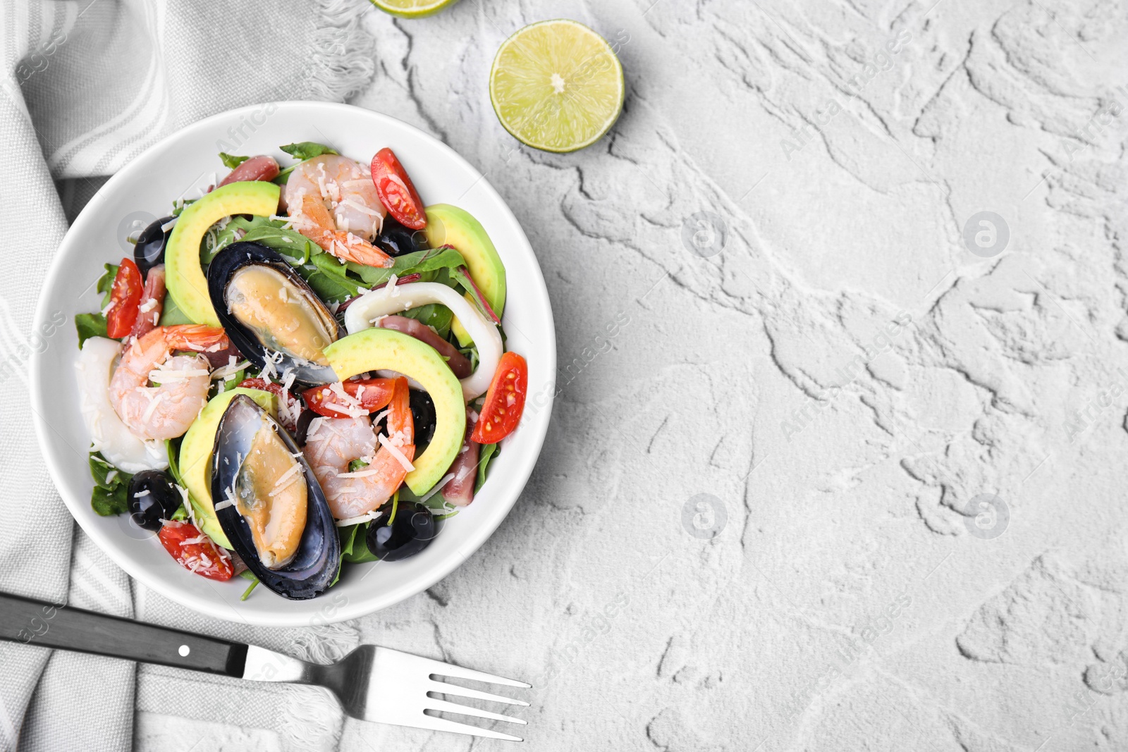 Photo of Bowl of delicious salad with seafood on white textured table, flat lay. Space for text