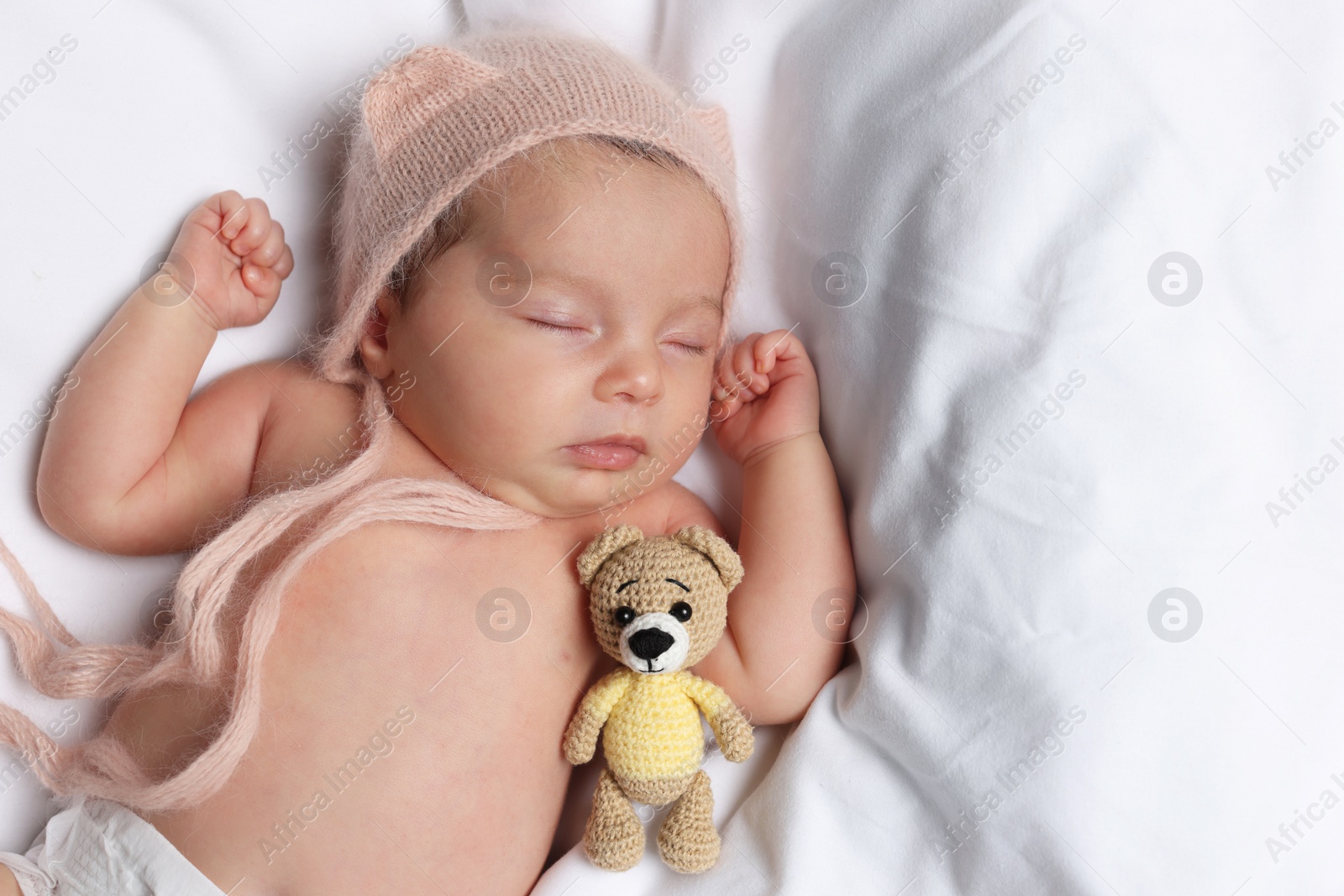 Photo of Cute little baby with toy bear sleeping on soft bed, top view