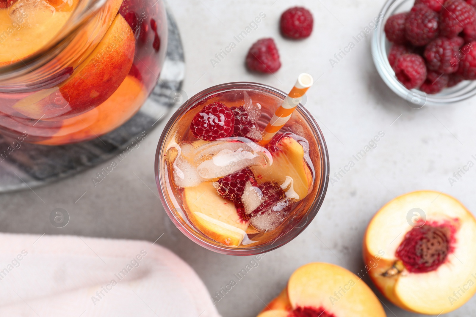 Photo of Delicious peach lemonade with soda water and raspberries on grey table, flat lay. Fresh summer cocktail