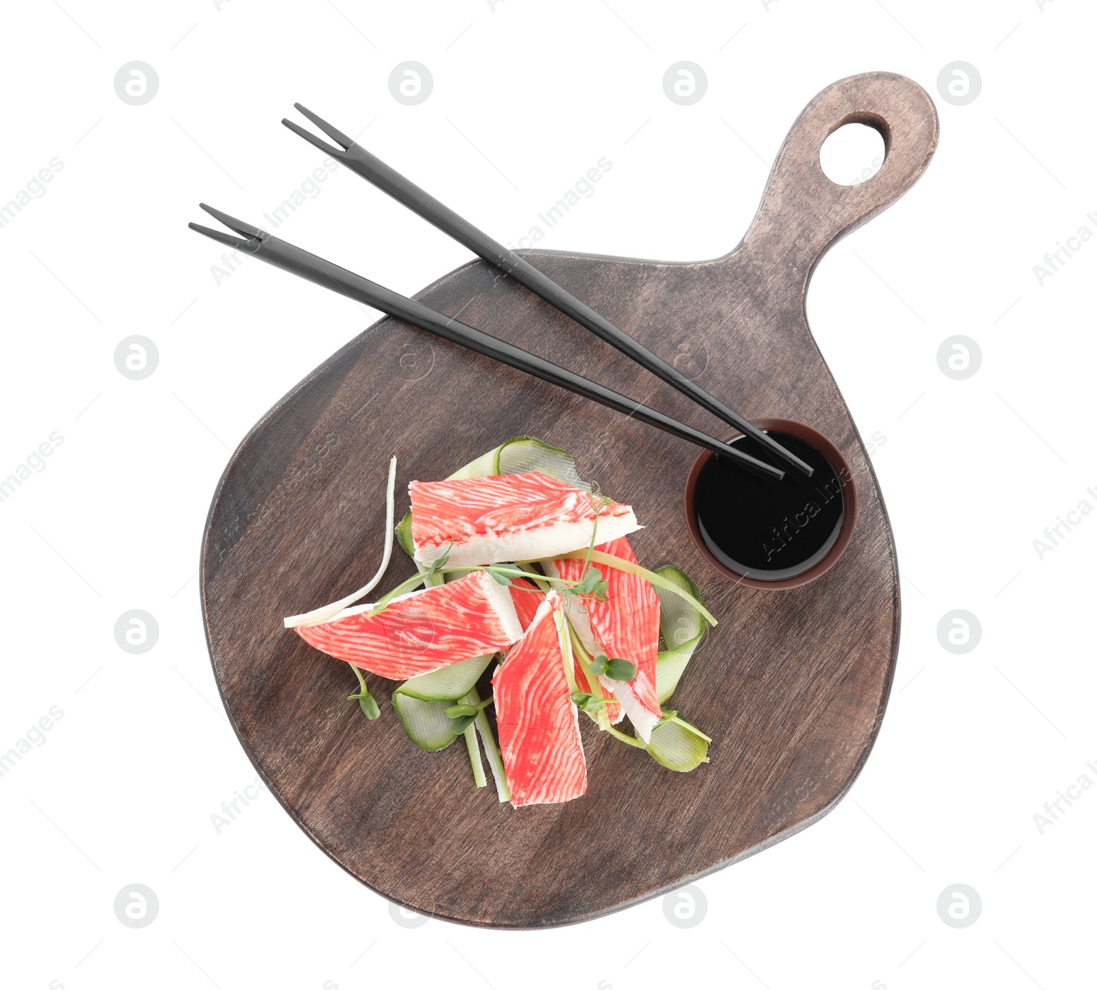 Photo of Serving board with fresh crab sticks, cucumber and soy sauce isolated on white