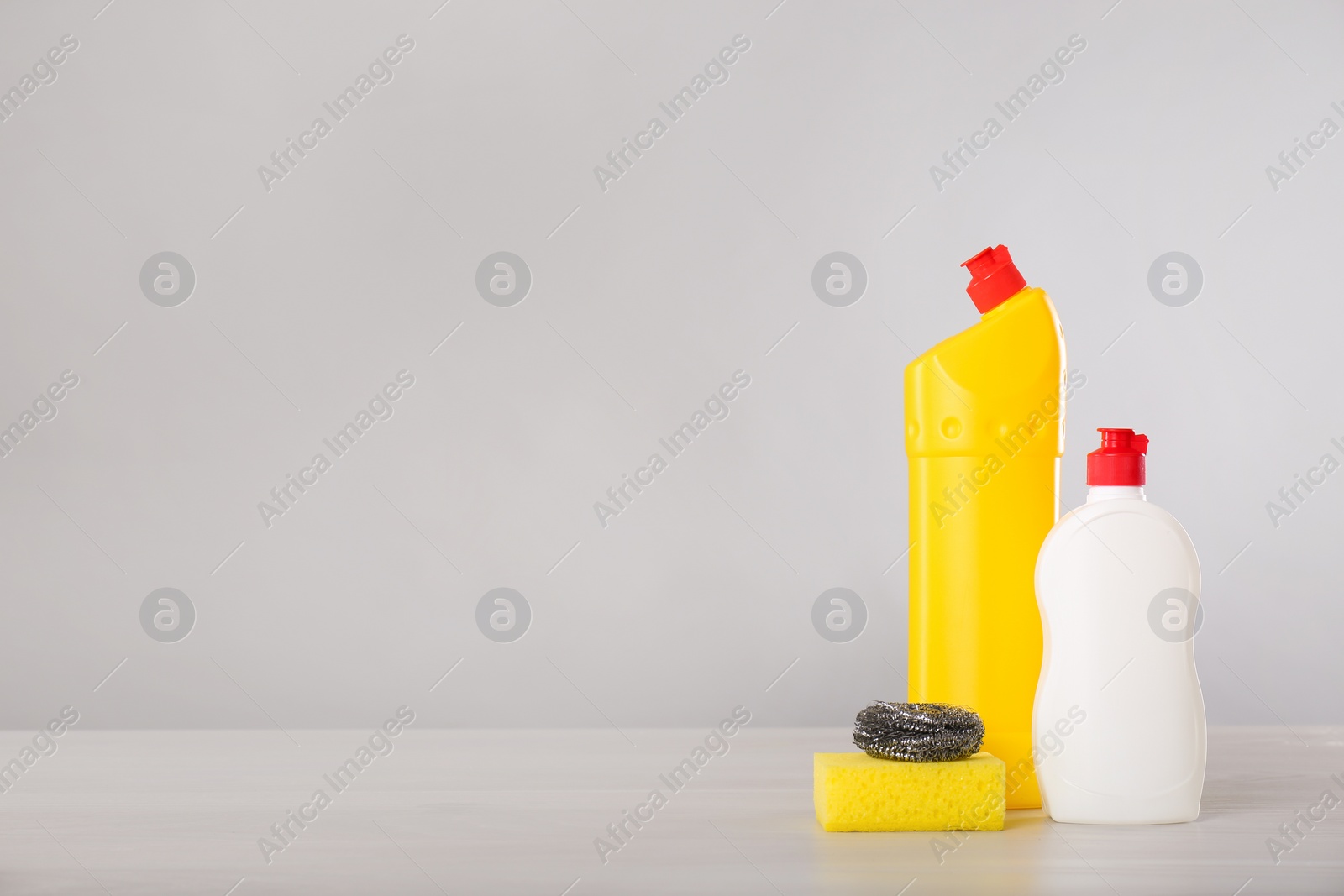 Photo of Bottles of cleaning products and supplies on light table. Space for text