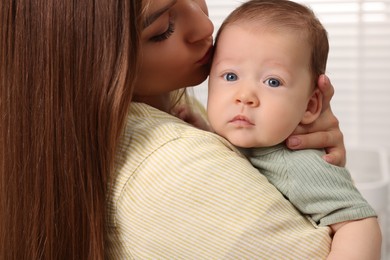 Mother holding her cute newborn baby at home, closeup