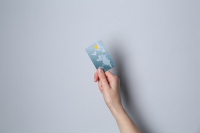 Photo of Woman holding credit card on light grey background, closeup