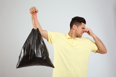 Photo of Man holding full garbage bag on light background