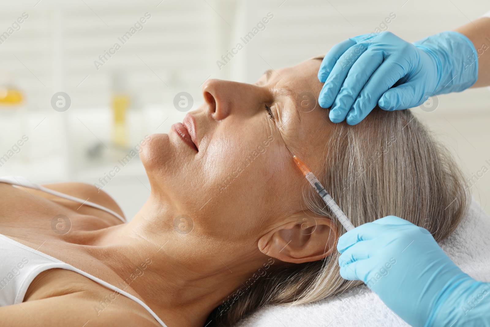 Photo of Doctor giving facial injection to senior woman in clinic, closeup. Cosmetic surgery