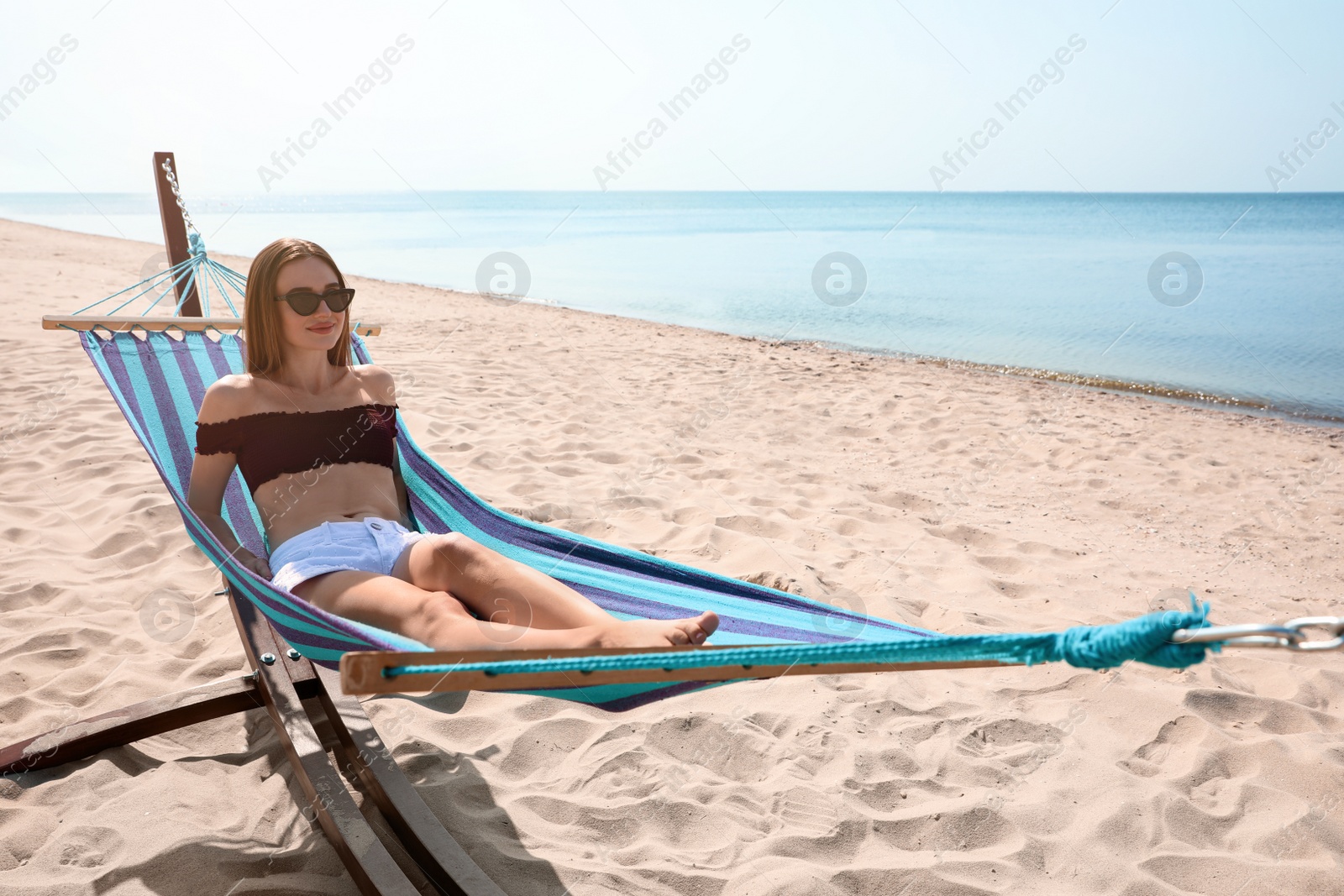 Photo of Young woman relaxing in hammock on beach