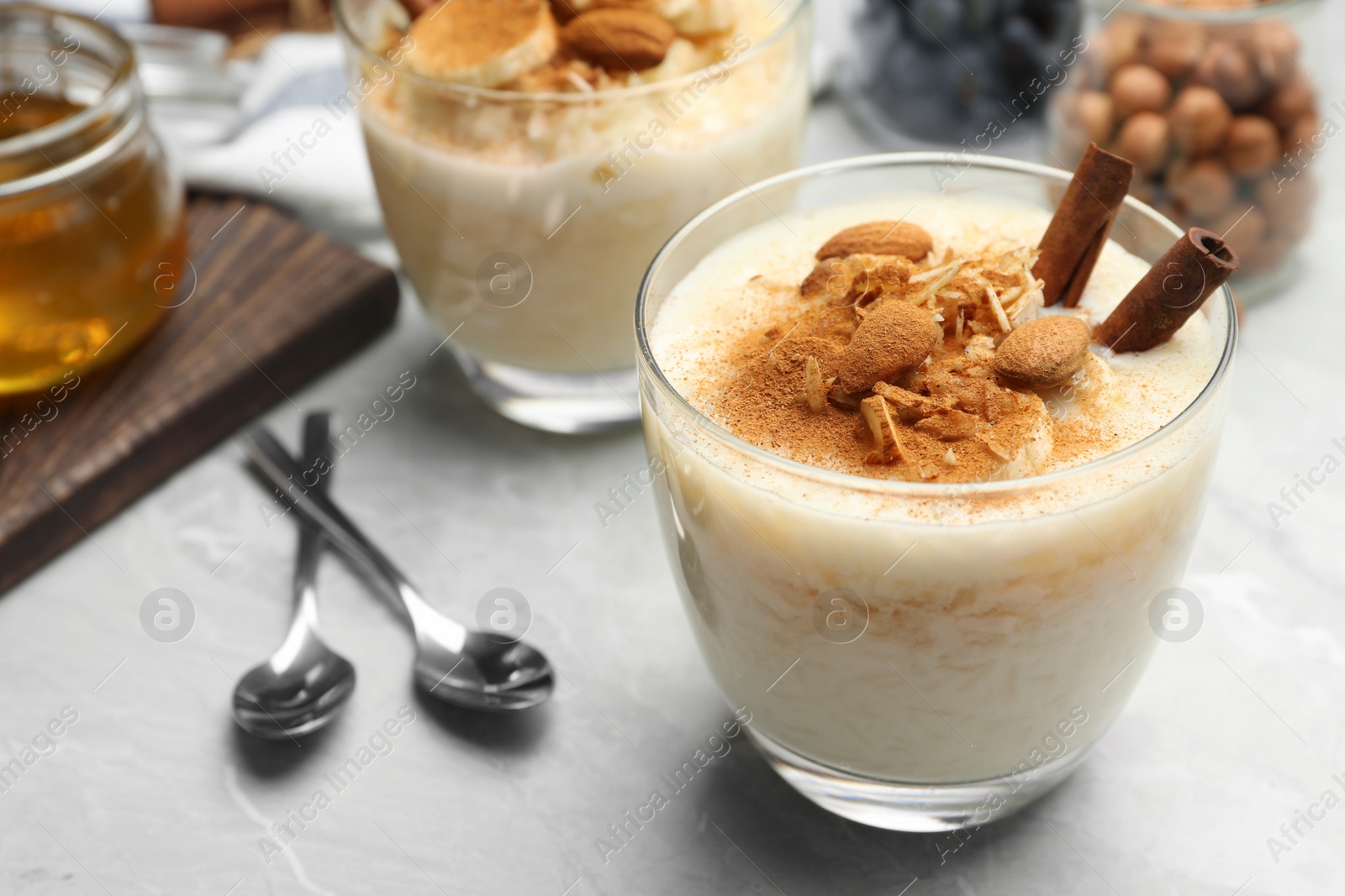 Photo of Delicious rice pudding with almonds and cinnamon on  marble table, closeup