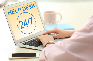 Image of Woman using laptop at table indoors, closeup. Help desk service