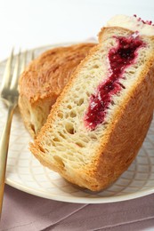 Round croissant with jam on table, closeup. Tasty puff pastry