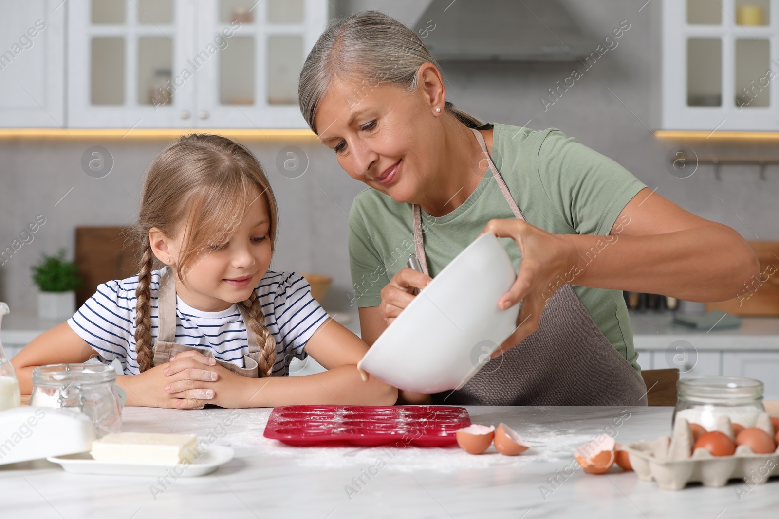 Photo of Happy grandmother with her granddaughter cooking together in kitchen