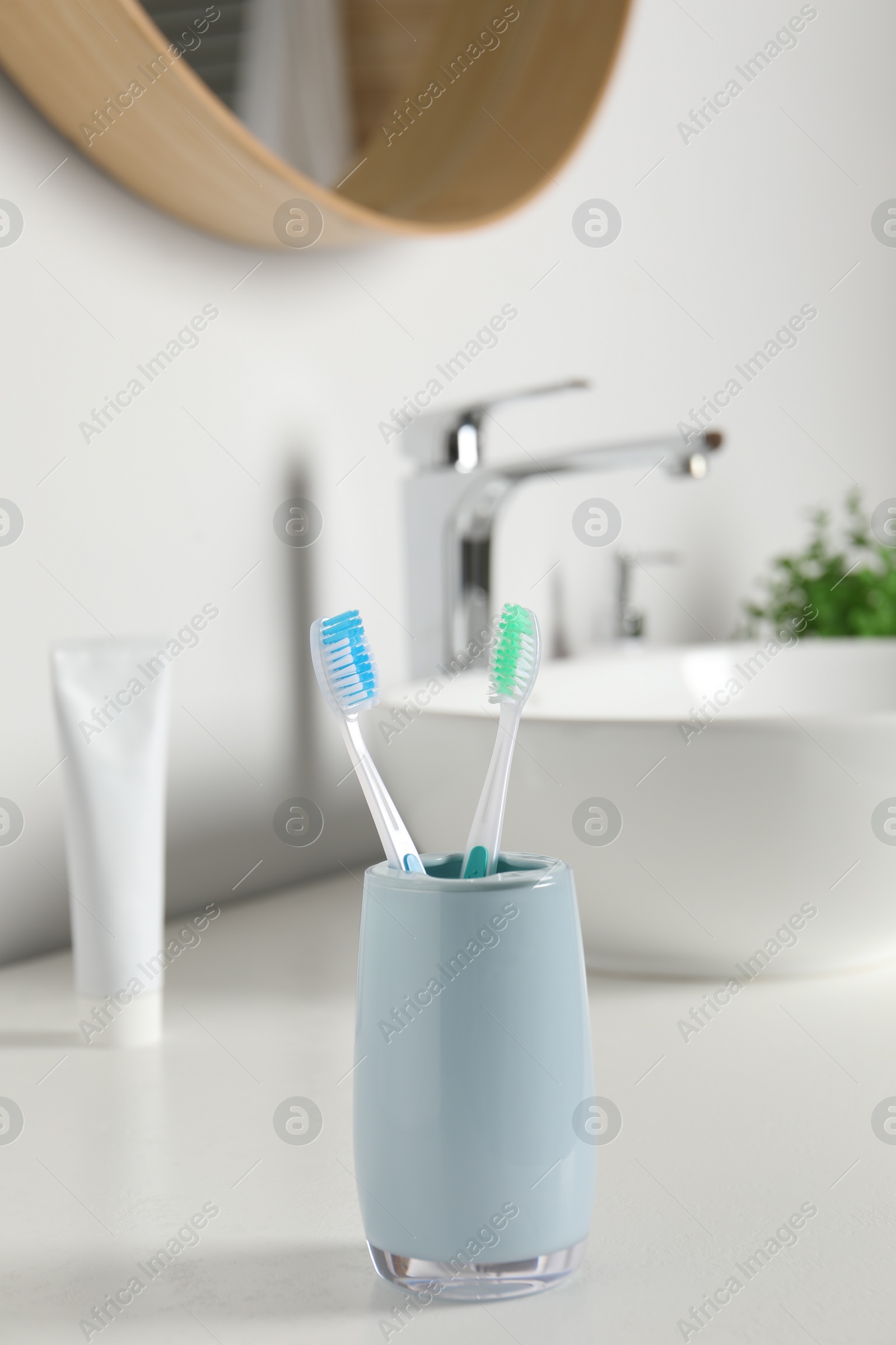 Photo of Plastic toothbrushes on white countertop in bathroom
