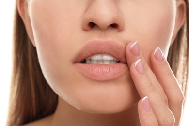 Image of Young woman with cold sore applying cream on lips, closeup