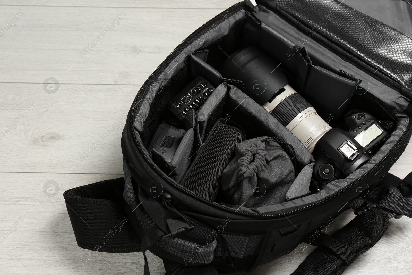 Photo of Backpack with professional photographer's equipment on wooden background