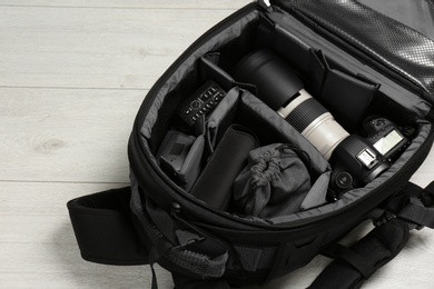 Backpack with professional photographer's equipment on wooden background