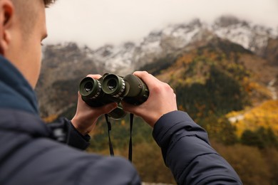 Boy holding binoculars in beautiful mountains, closeup. Space for text