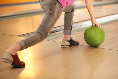 Photo of Child throwing ball in bowling club, closeup