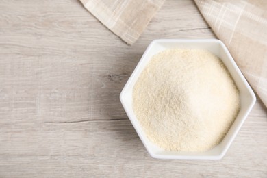 Photo of Gelatin powder in bowl on white wooden table, top view. Space for text