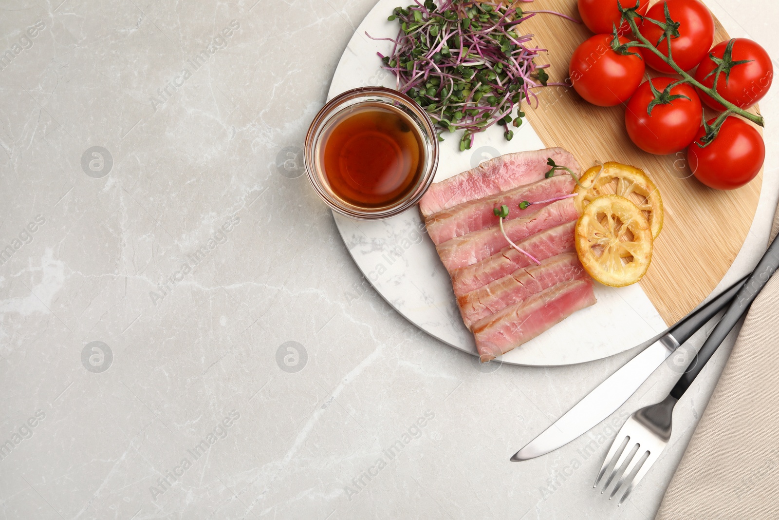 Photo of Pieces of delicious tuna steak served on light grey marble table, flat lay. Space for text