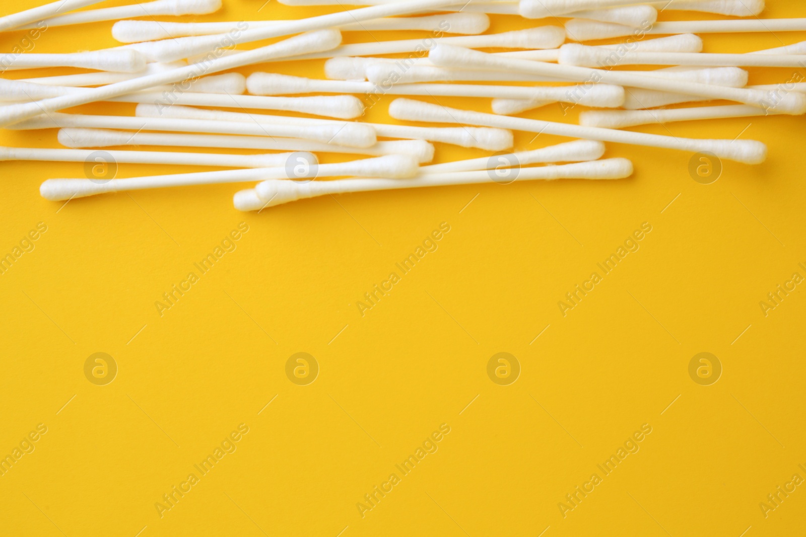 Photo of Many clean cotton buds on yellow background, flat lay. Space for text