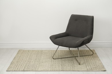 Photo of Stylish grey armchair near white wall indoors. Space for text