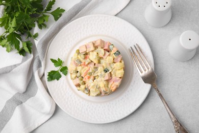 Photo of Tasty Olivier salad with boiled sausage served on light grey table, flat lay