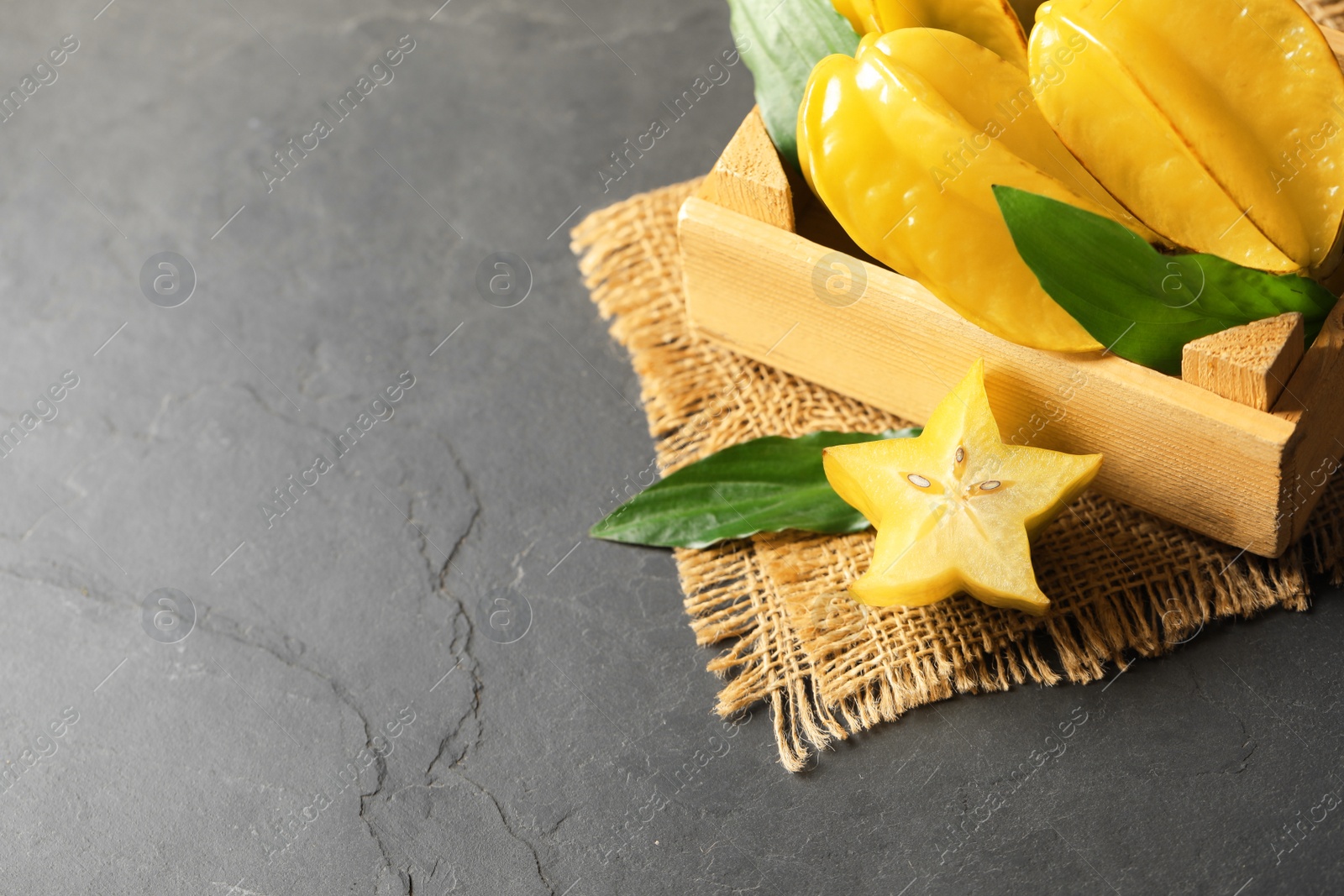 Photo of Delicious carambola fruits on black table, above view. Space for text