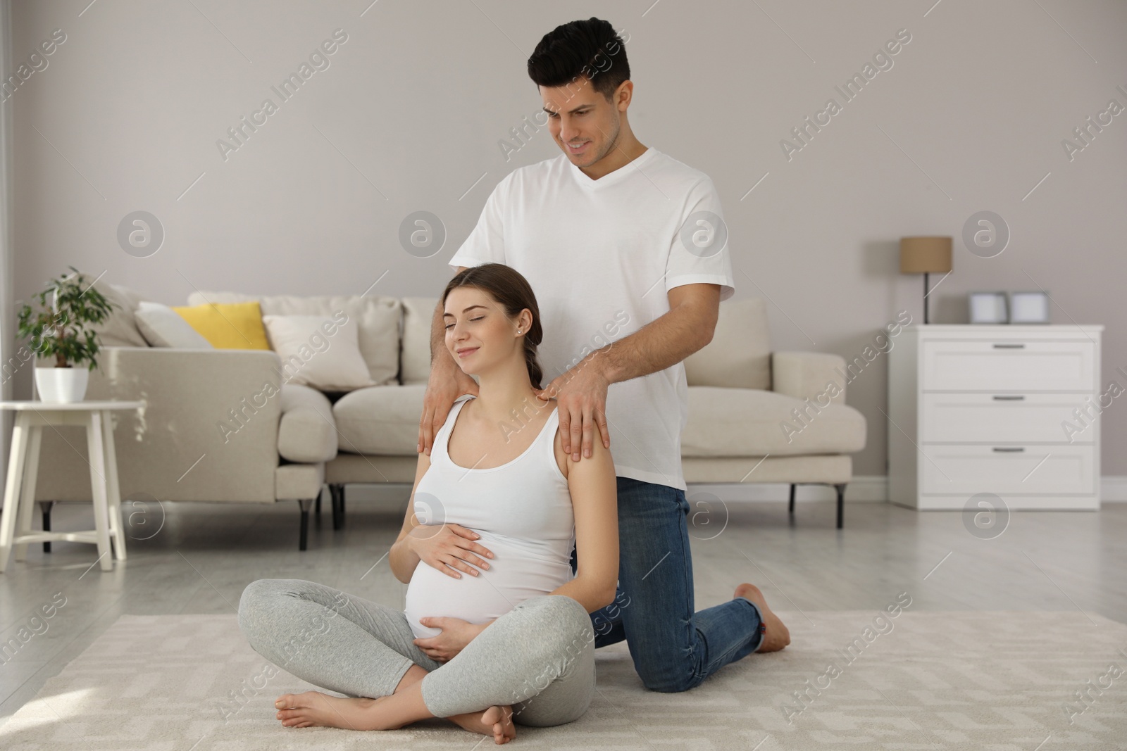 Photo of Husband massaging his pregnant wife in living room. Preparation for child birth
