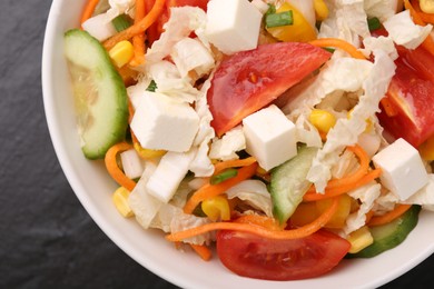 Photo of Tasty salad with Chinese cabbage, carrot, cheese, cucumber, corn and tomato on black table, top view